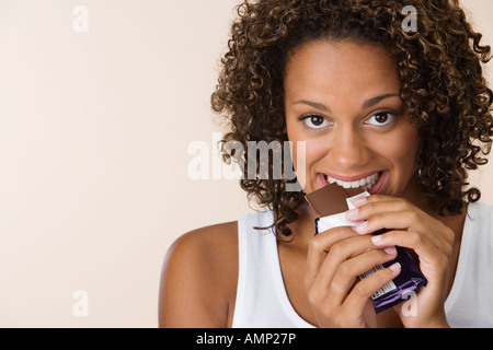 African woman eating chocolate bar Banque D'Images