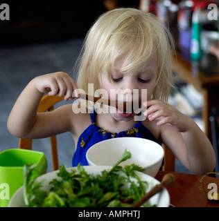 Alimentation bébé fille elle-même avec une cuillère. 2007 Banque D'Images