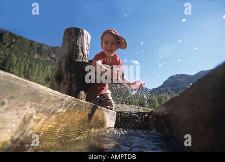 Boy sitting on tree trunk Banque D'Images