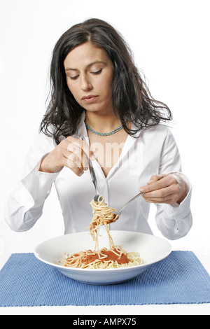 Young woman eating plat de spaghetti avec une fourchette, portrait Banque D'Images