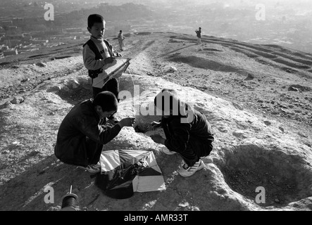 Les garçons réparer leur cerf-volant sur une colline à Kaboul Afghanistan Août 2005 Banque D'Images