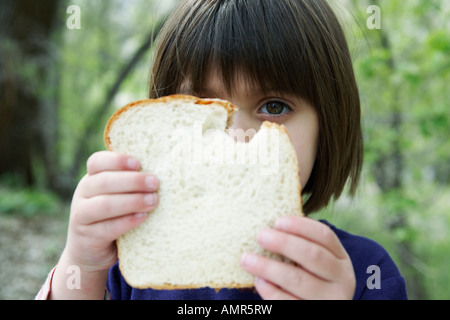 Little girl holding sandwich avec un morceau manquant. Banque D'Images