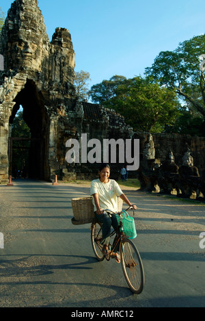 Femme en vélo à la Porte Sud d'Angkor Thom au Cambodge Banque D'Images