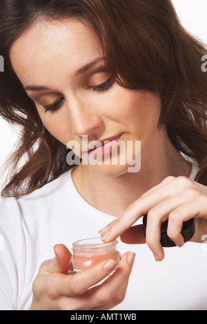 Woman Putting On Lip Gloss Banque D'Images