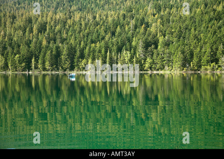 Un bateau blanc sur le lac entouré d'un bois dense Banque D'Images