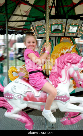 5 ans, fille en robe rose pink pony rides sur merry go round Banque D'Images