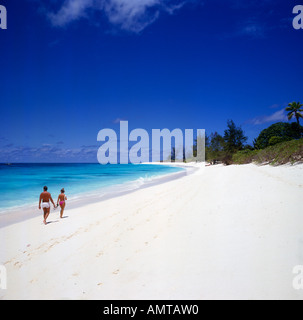 Vue arrière du couple se promener le long de l'autre rêve déserte-comme le style de l'île désertique de l'île Bird plage aux Seychelles Banque D'Images