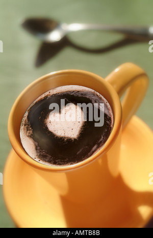 Une tasse fumante de cappuccino avec un soupçon de en forme de coeur au milieu de la mousse Banque D'Images