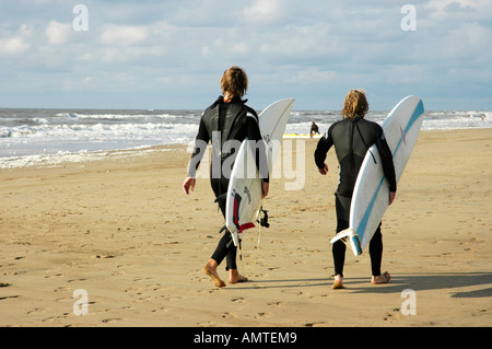 Deux jeunes hommes dans un wetsuite réalisent des planches de surf à la plage, Katwijk aan Zee, Pays-Bas du Sud, Hollande, Pays-Bas Banque D'Images