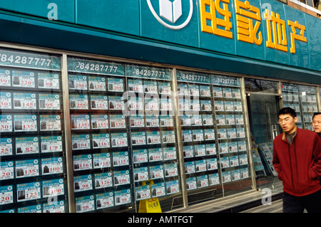 Un homme passe devant une fenêtre de l'agent immobilier où des cartes de couleur annoncer maisons et appartements à louer ou acheter. 18 déc 2007 Banque D'Images