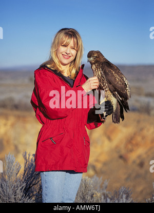 Une femme falconer avec une buse à queue rouge prenant part à la fauconnerie sportives sur le haut désert près de Bend Banque D'Images