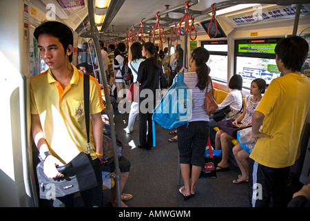 Les passagers portant des chemises jaunes à faire preuve de respect pour le Roi de Thaïlande à l'intérieur d'une station du Skytrain, transport. Bangkok, Thaïlande Banque D'Images