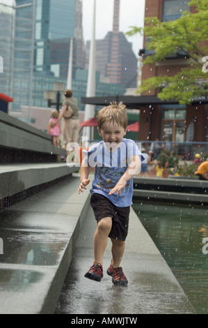 Trois ans s'amusant sur une journée d'été par l'exécution par le biais d'un sprinkleur de l'eau au centre-ville de Baltimore Maryland 2005 Banque D'Images