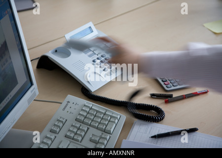 Portrait de personne assise en face de PC de bureau et de tenir le récepteur de téléphone Banque D'Images