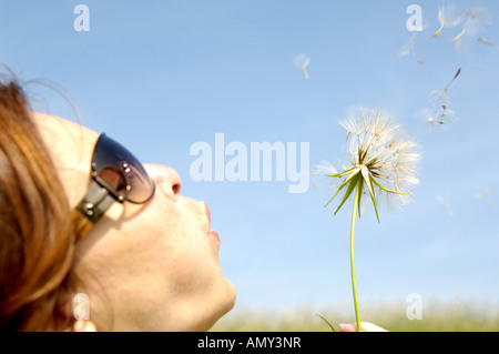 Close-up of mid adult woman blowing dandelion Banque D'Images