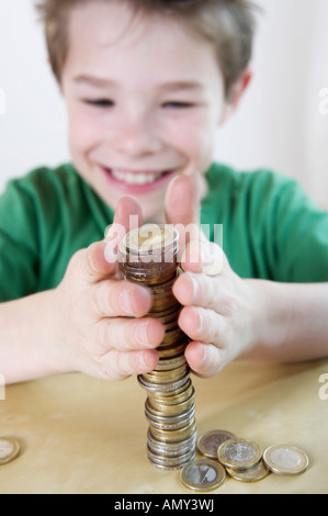 Close-up of boy stacking coins and smiling Banque D'Images