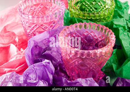 Ensemble de trois multi-verre verres colorés, être enveloppé dans le rose, vert et lilas de papier tissu à un cadeau. Banque D'Images