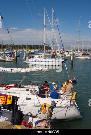 Les gens se détendre assis sur la poupe du yacht dans le port de Yarmouth avec d'autres bateaux de luxe amarré à l'île de Wight en Angleterre Banque D'Images