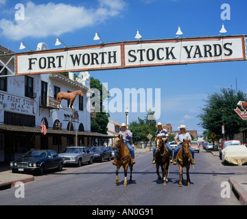 Trois cowboys à cheval posant pour l'appareil photo sous un signe en échange Avenue à Fort Worth Stock Yards Texas USA Banque D'Images