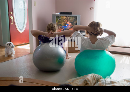 Deux adolescentes suivent un chien de famille tout en vidéo pilates montres dans le salon de la famille Banque D'Images