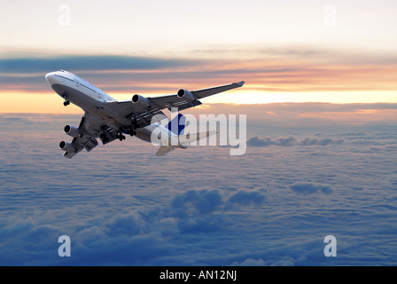 Grand vol d'un avion de passagers au-dessus des nuages et le coucher du soleil Banque D'Images