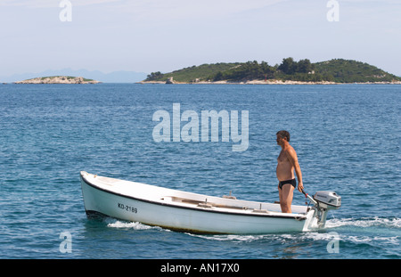 Un homme debout, dans un petit bateau avec un moteur hors-bord Honda sur le bleu de la mer, des îles dans l'arrière-plan Orebic ville, station balnéaire sur la côte sud de la péninsule de Peljesac. Orebic ville. Péninsule de Peljesac. La côte dalmate, en Croatie, en Europe. Banque D'Images