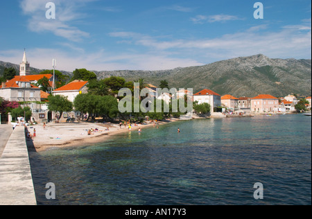 La plage avec les nageurs et les baigneurs sun avec le village et les montagnes en arrière-plan. Mont mont. Orebic ville, station balnéaire sur la côte sud de la péninsule de Peljesac. Orebic ville. Péninsule de Peljesac. La côte dalmate, en Croatie, en Europe. Banque D'Images