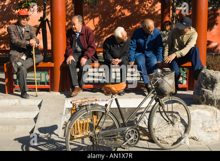 Chine Pékin près de Beihai Park les personnes âgées rencontre groupe d'hommes parlant sous véranda avec avec vélo dans frgd Banque D'Images