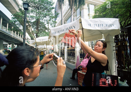 Thaïlande, Bangkok, Woman Taking Photo d'une femme qui le mérite en libérant des oiseaux en cage au sanctuaire d'Erawan Banque D'Images