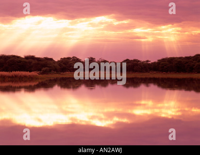 Rayons de soleil percer les nuages à un lac avec réflexion Mont Etjo Afrique Namibie Banque D'Images