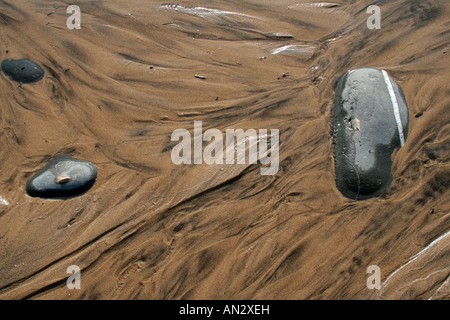 Vent de sable soufflé à la plage parmi les pierres noires Côte ouest de l'Algarve au Portugal Europe Banque D'Images