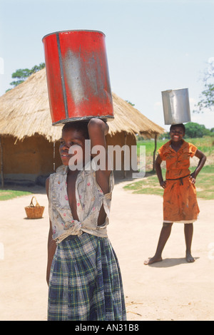 Les jeunes filles de porter des seaux d'eau qui fuit au Zimbabwe Banque D'Images
