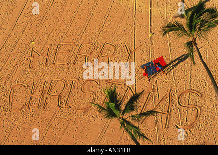 Regardant le message dans le sable en disant Joyeux Noël sur la plage à Hawaii Banque D'Images