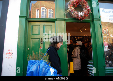 Décembre 2007 London Columbia Road. Femme transportant petit arbre en sac à l'extérieur de l'atelier Banque D'Images
