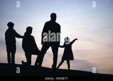 Silhouette de la famille sur la colline regardant ciel du soir Banque D'Images