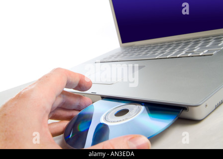 Man putting disc CD dans le lecteur de disque sur un ordinateur portable Banque D'Images