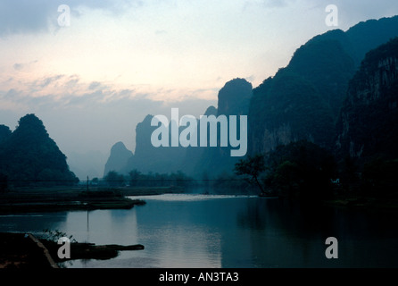 Près de la rivière Li Fuli Chine avec Misty montagnes karstiques sombres se profilent le long de ses rives Banque D'Images