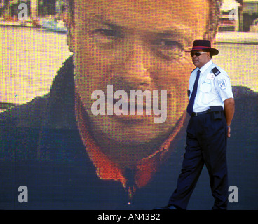 Un garde de sécurité marche devant un grand écran de télévision dans l'America's Cup Village de Auckland au cours de l'événement 2000 Banque D'Images