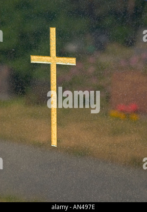 Croix d'or sur la pierre tombale et réflexions des fleurs sur la tombe Banque D'Images