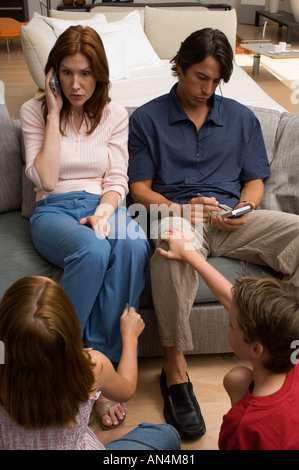 Portrait de deux enfants la peine à leurs parents qui sont sur le téléphone Banque D'Images