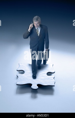 Businessman walking sur un morceau de puzzle Banque D'Images