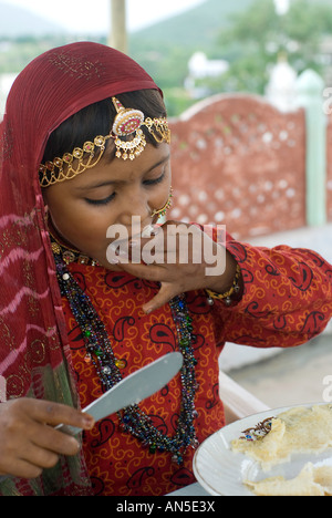 Portrait d'une jeune fille en costume traditionnel Rajasthani manger une crêpe, Rajasthan (Inde) Banque D'Images