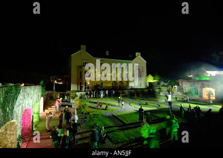 Les jeunes comédiens interprétant une pièce à jardins Aberglasney Llandeilo Carmarthenshire dans la nuit avec des projections vidéo sur un mur extérieur Banque D'Images