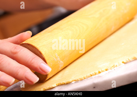 Rouler la pâte sablée femme avec un rouleau à pâtisserie sur la plaque de marbre Banque D'Images