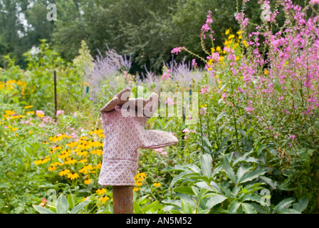 Concept de jardinage glove sur un post dans un jardin de fleurs Banque D'Images