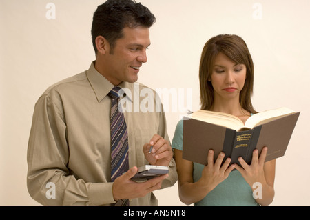 Portrait d'un homme à l'aide de son Palm Pilot tandis qu'une femme lit un livre Banque D'Images