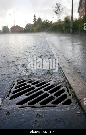 L'eau de pluie qui s'écoule dans un tuyau d'évacuation sur le côté d'une route à Redditch UK Worcestershire pendant un orage d'été Banque D'Images