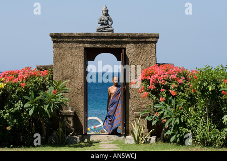 L'homme en Sarong balinais en statue de Bouddha sur la plage Amed Bali Indonésie Banque D'Images