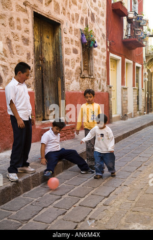 Mexique Guanajuato quatre enfants mâles joue au soccer dans ruelle étroite entre les bâtiments bâtiments colorés Banque D'Images