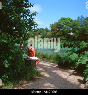 Une femme assise par un étang au Jardin Botanique National du Pays de Galles, Carmarthenshire, Pays de Galles UK KATHY DEWITT Banque D'Images